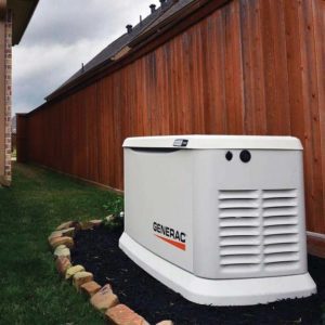 Generac backup generator installed beside a wooden fence in a residential yard