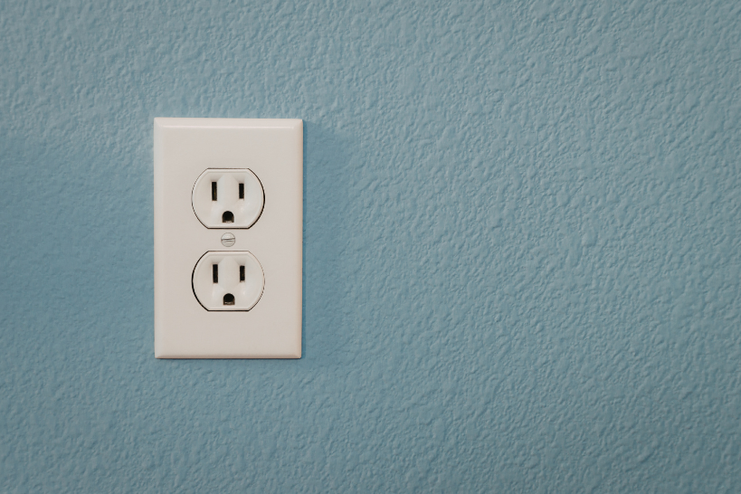 Standard white duplex electrical outlet on a blue painted wall.