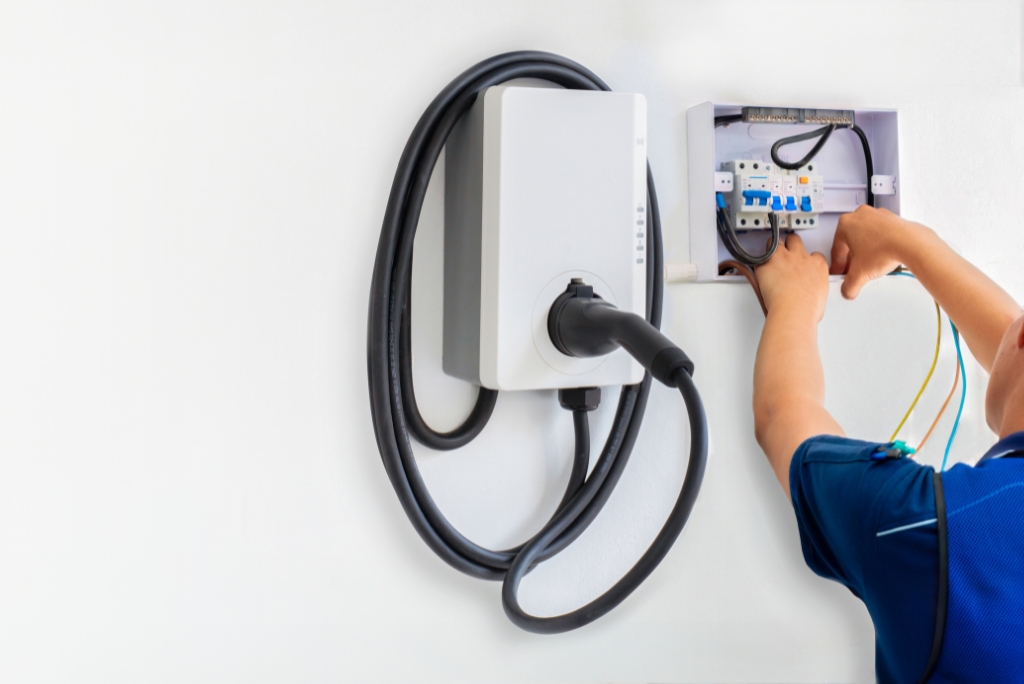 Electrician wiring a wall-mounted EV charger and dedicated electrical circuit in Austin, TX.