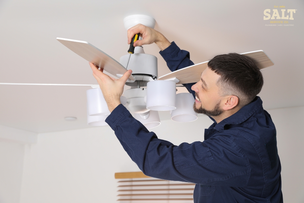 Electrician installing a ceiling fan, representing ceiling fan installation costs in Austin, TX.