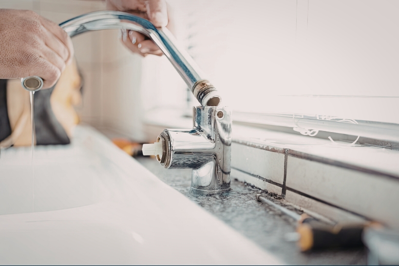 Plumber disassembling a bathroom faucet to repair or replace the internal cartridge.