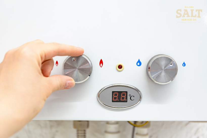 Homeowner adjusting a water heater control while considering repair or replacement in Austin, TX.
