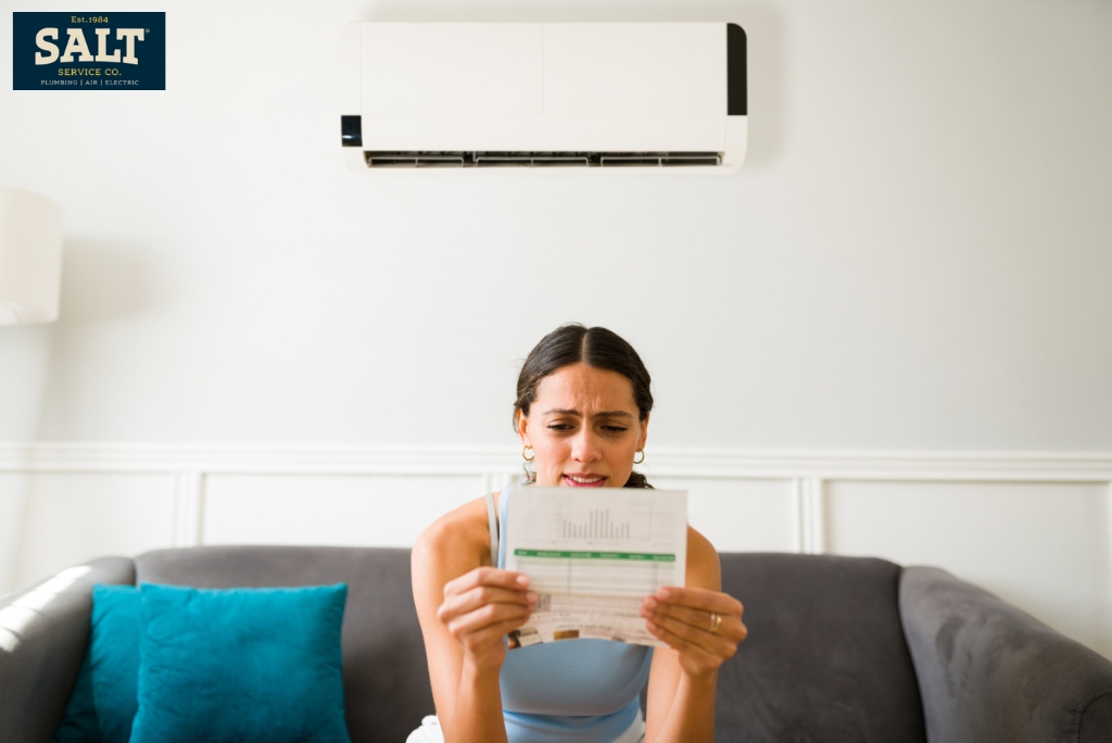 Homeowner reviewing a high summer electric bill, a potential warning sign of an inefficient or failing AC system.